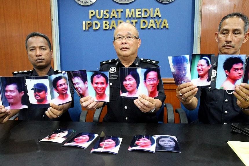 Malaysian police officers show portraits of people allegedly involved in a nudist sports festival, during a press conference in Penang on Aug 8, 2014. -- PHOTO: AFP