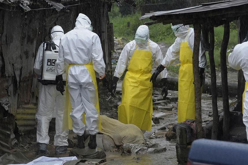 Health workers wearing protective clothing prepare to carry an abandoned dead body presenting with Ebola symptoms at Duwala market in Monrovia on Aug 17, 2014.&nbsp;Cases in West Africa's Ebola outbreak this year have risen to 2,240, including 1,229 