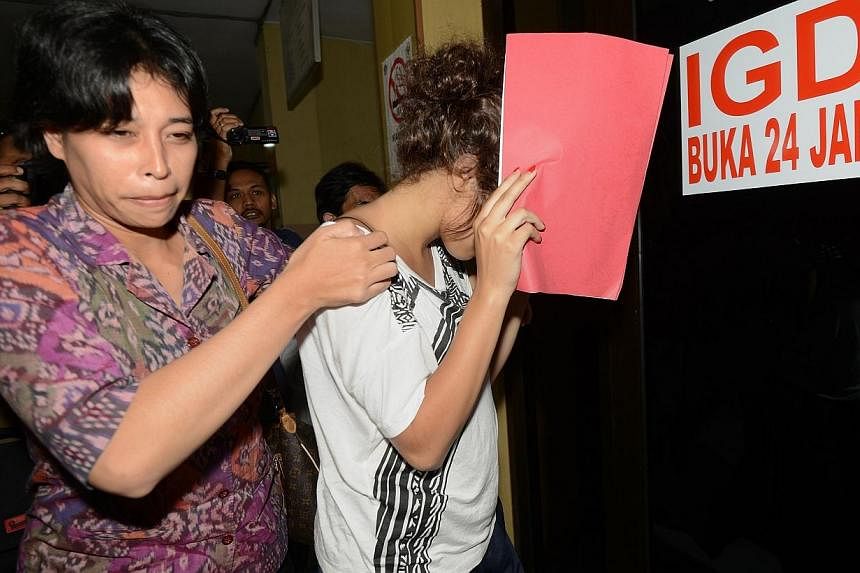A policewoman escorts Heather Mack (right), suspected in the murder of her mother Sheila von Wiese Mack, while in custody at Bali police hospital in Denpasar on the Indonesian resort island of Bali on Aug 15, 2014 after authorities said they were on 