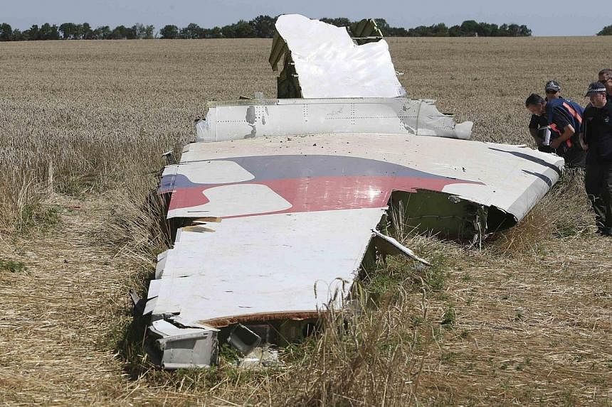 Members of a group of international experts inspect wreckage at the site where the downed Malaysia Airlines flight MH17 crashed, near the village of Hrabove (Grabovo) in Donetsk region, eastern Ukraine on Aug 1, 2014. -- PHOTO: REUTERS