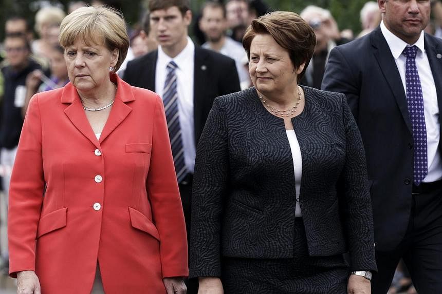 Latvia's Prime Minister Laimdota Straujuma and Germany's Chancellor Angela Merkel arrive to attend a wreath-laying ceremony in Riga August 18, 2014. Dr Merkel on Monday promised the Baltic states that Nato would defend them, although it would not sen