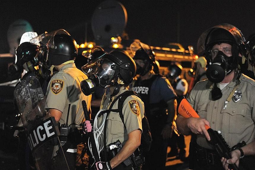 Law enforcement offices watch on during a protest on West Florissant Avenue in Ferguson, Missouri on Aug 18, 2014.&nbsp;The police came under "heavy gunfire" and 31 people were arrested, the authorities said on Tuesday, in racial unrest in Ferguson, 