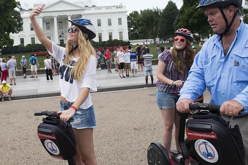 A tourist riding a Segway takes a "selfie" with her camera phone outside the White House in Washington, DC, on Aug 11, 2014. -- PHOTO: AFP