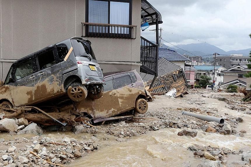 Cars damaged by a landslide lie in mud and debris after heavy rains hit the city of Hiroshima, western Japan, on Aug 20, 2014.&nbsp;A huge landslide that engulfed homes in western Japan killed at least 39 people and left another seven missing, the go