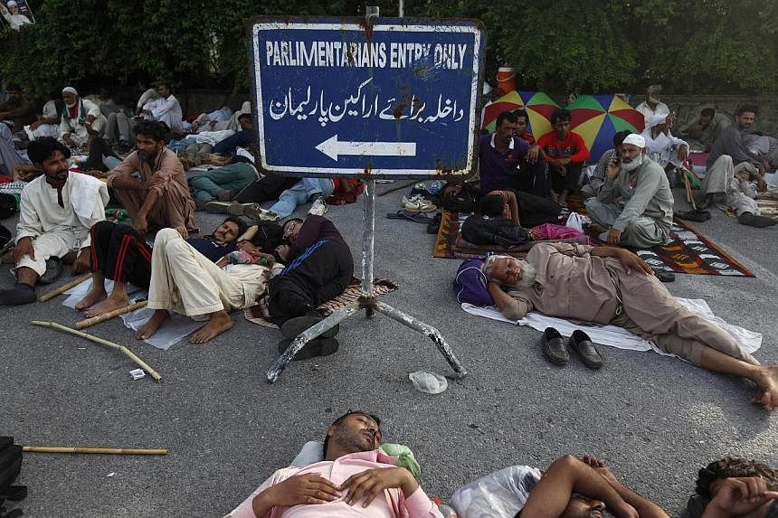 Supporters of Pakistani cleric&nbsp;Mohammad Tahir ul-Qadri sleep at the entrance of the parliament house in Islamabad on Aug 20, 2014. -- PHOTO: REUTERS