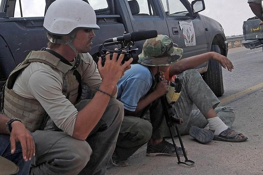 A file picture taken on September 29, 2011 shows US freelance reporter James Foley (left) on the highway between the airport and the West Gate of Sirte, Libya.&nbsp;Twitter on Wednesday removed from its service photos and video of the beheading of Fo