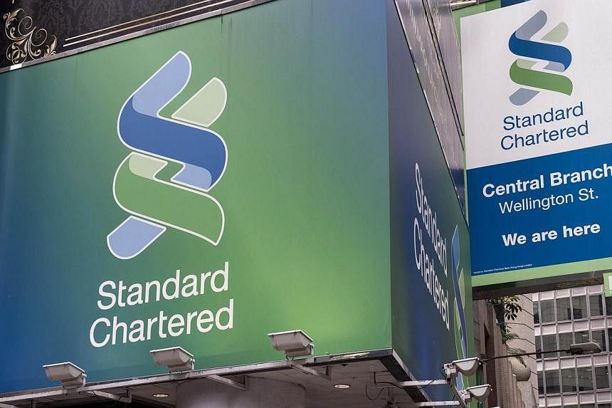 An August 6 2014 photo shows Standard Chartered billboards as they hang above a bank branch in Hong Kong. New York's banking regulator hit Standard Chartered Bank with a US$300 million (S$374 million) fine and restrictions on its dollar-clearing busi