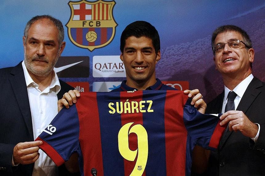 Barcelona's new Uruguayan forward Luis Suarez (center) poses with Barcelona's sports director Andoni Zubizarreta (left) and Barcelona's vice-president Jordi Mestre during his official presentation at the Camp Nou stadium in Barcelona. -- PHOTO: AFP