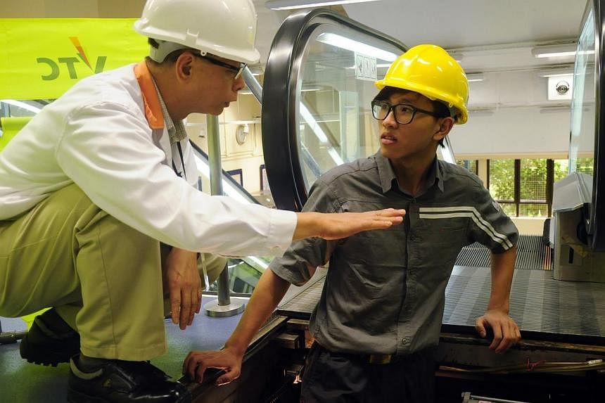 Trainee Wong Sheung Man (right) getting tips on how to repair a stuck escalator at the Vocational Training Council (VTC) campus. -- PHOTO: PEARL LIU