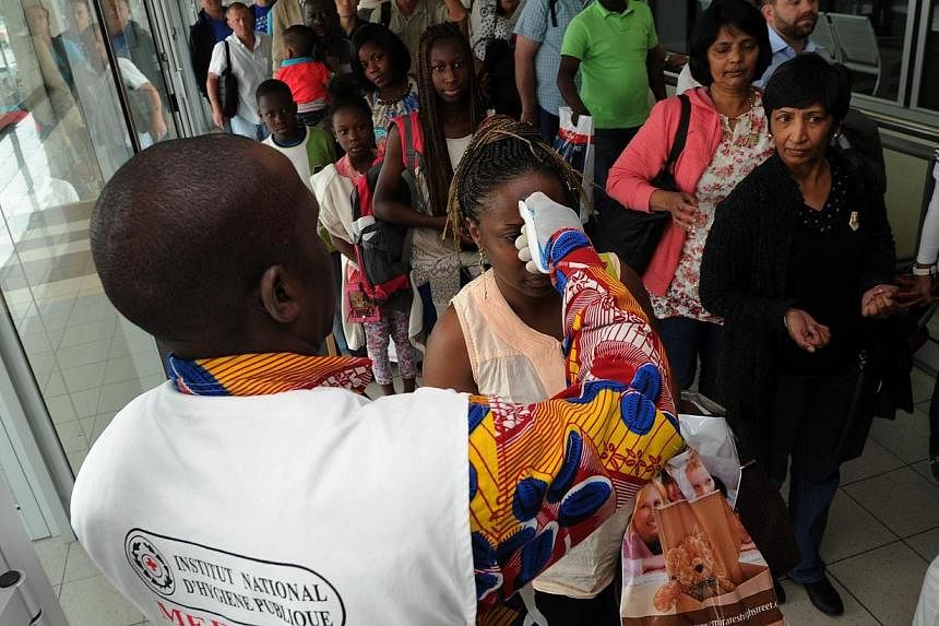 A doctor of the national public health institute controls the temperature of people at the airport, in Abidjan on Aug 13, 2014, as part of protective measures against the Ebola virus.&nbsp;South Africa on Thursday issued a ban on non-citizens travell