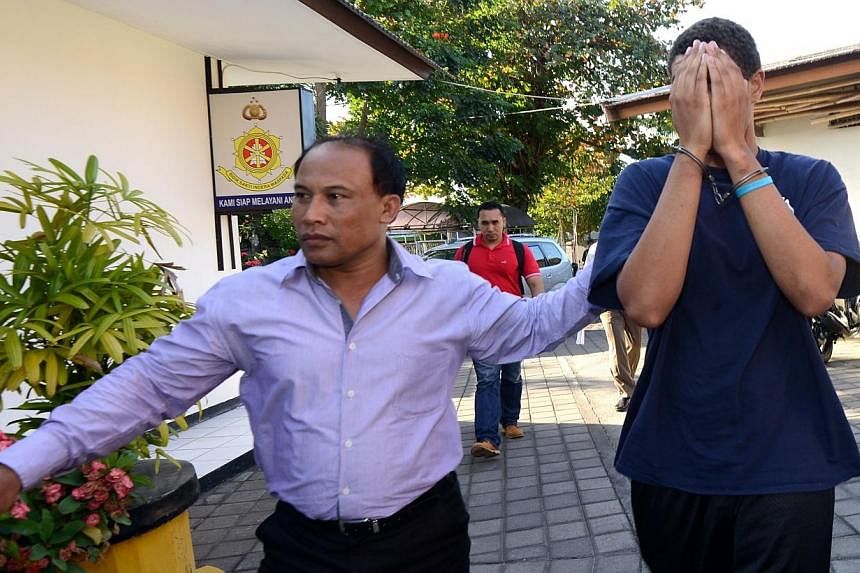 A police officer escorts suspect Tommy Schaefer, 21, (right) during an investigation at a police office in Nusa Dua on Indonesian resort island of Bali on Aug 13, 2014. -- PHOTO: AFP