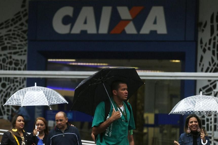 People walk past a Caixa Economica Federal bank in downtown Rio de Janeiro August 14, 2014. Banks in Brazil will be allowed to use up to 60 per cent of reserves for credit operations, an increase from the 50 per cent limit announced on July 25.&nbsp;