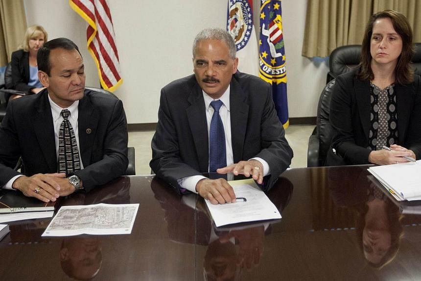 US Attorney General Eric Holder (centre) during his meeting with Special Agent in Charge William P. Woods (left) and Acting Assistant Attorney General for Civil Rights Molly Moran at the FBI building in St. Louis, Missouri. -- PHOTO: AFP