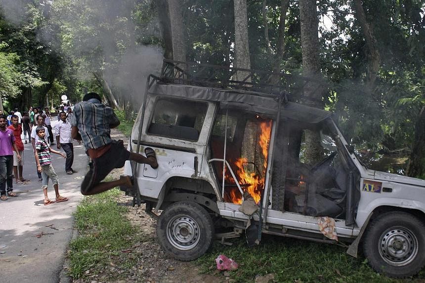 A demonstrator kicks a vehicle that was set on fire during a protest at Golaghat district in the northeastern Indian state of Assam on August 20, 2014. Thousands of protesters in the far-flung Indian state of Assam defied a curfew and attacked police