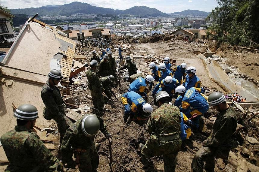 Japan Self-Defense Force (JSDF) soldiers and police officers search for survivors at a site where a landslide swept through a residential area at Asaminami ward in Hiroshima, western Japan, on Aug 21, 2014. -- PHOTO: REUTERS
