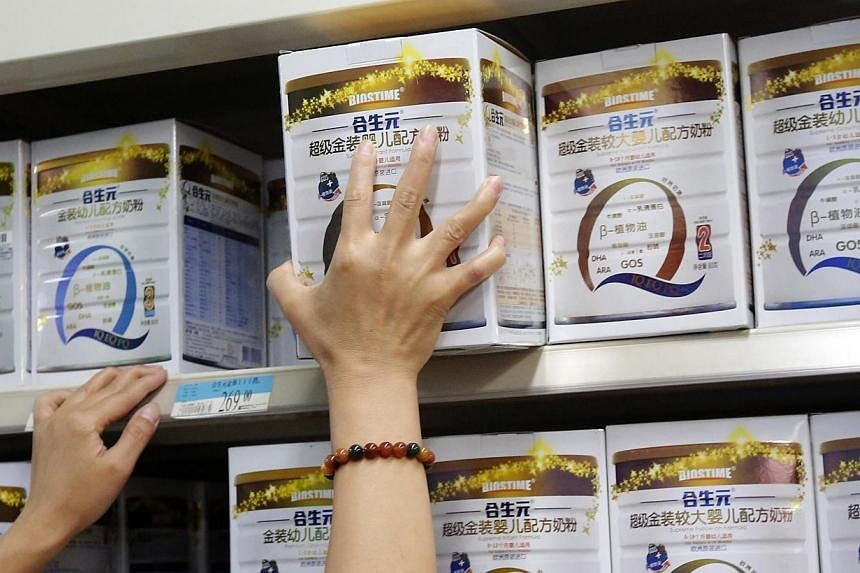 A store assistant arranges Biostime's milk powder products on a shelf at a supermarket in Beijing on Aug 7, 2013.&nbsp;A Chinese retailer is offering insurance to customers who buy infant milk powder, highlighting the lengths to which companies are g