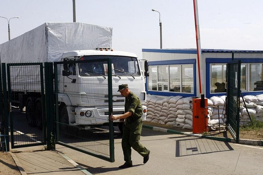 A man opens the gate to let lorries, part of a Russian humanitarian convoy, cross the Ukrainian border at the Izvarino custom control checkpoint on Aug 22, 2014.&nbsp;Ukraine on Friday, Aug 22, 2014, accused Moscow of invading after Russia unilateral