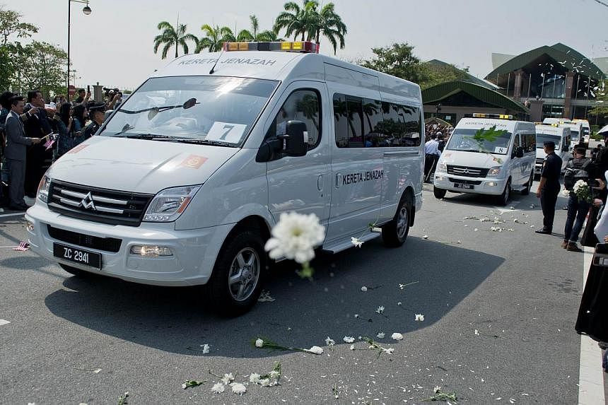 Malaysia Airlines flight attendants (unseen) throw white flowers as a convoy of hearses carrying the remains of the victims of Malaysia Airlines flight MH17 at the Bunga Raya complex in Sepang on Aug 22, 2014. -- PHOTO: AFP&nbsp;