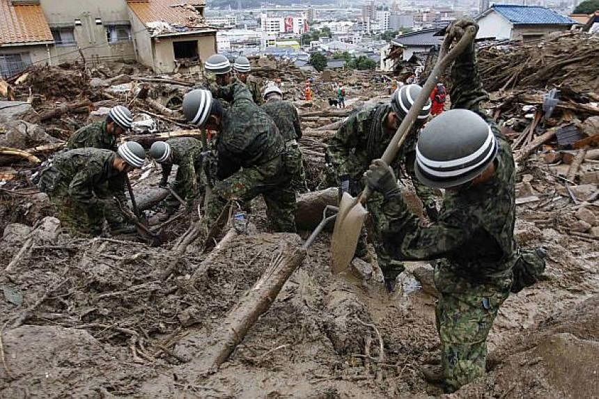 Japan Self-Defence Force (JSDF) soldiers search for survivors in the rain at a site where a landslide swept through a residential area at Asaminami ward in Hiroshima, western Japan, on Aug 22, 2014. -- PHOTO: REUTERS