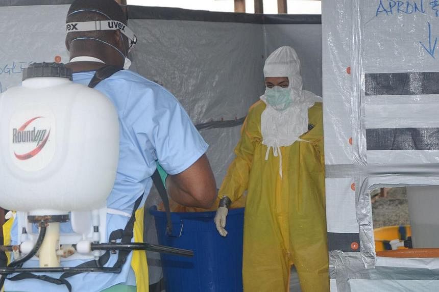 A nursing staff disinfects a doctor's outfit at the French NGO Medecins Sans Frontieres (Doctors without borders) Elwa hospital in Monrovia, where patients suffering from Ebola are taken care of, on Aug 21, 2014. -- PHOTO: AFP