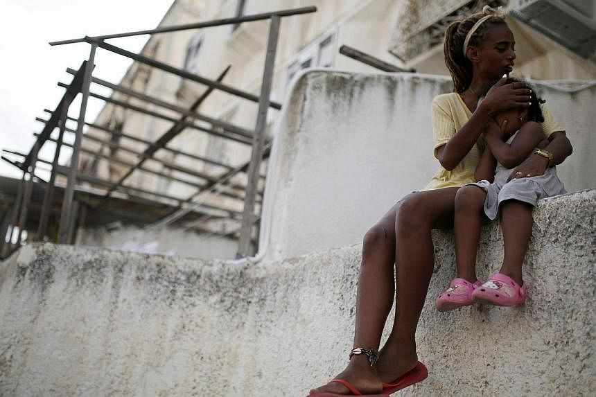A woman holds her daughter next to a synagogue that was damaged by a rocket in the southern city of Ashdod on Aug 22, 2014. A mortar bomb fired from Gaza killed a four-year-old Israeli boy, in a border collective farm on Friday, Israeli security sour