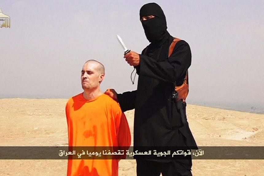 A masked Islamic State militant holding a knife speaks next to man purported to be US journalist James Foley at an unknown location in this still image from an undated video posted on a social media website. -- PHOTO: REUTERS