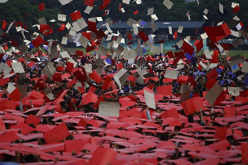 Participants toss placards into the air after completing an attempt to break the Guinness World Record for the "Largest Human National Flag" at Tundhikhel in Kathmandu Aug 23, 2014. -- PHOTO: REUTERS