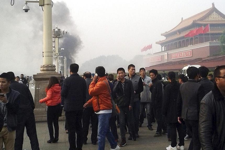 People walk along the sidewalk of Chang'an Avenue as smoke rises in front of the main entrance of the Forbidden City at Tiananmen Square in Beijing in this October 28, 2013 file photo. China has executed eight people for "terrorist" attacks in its re