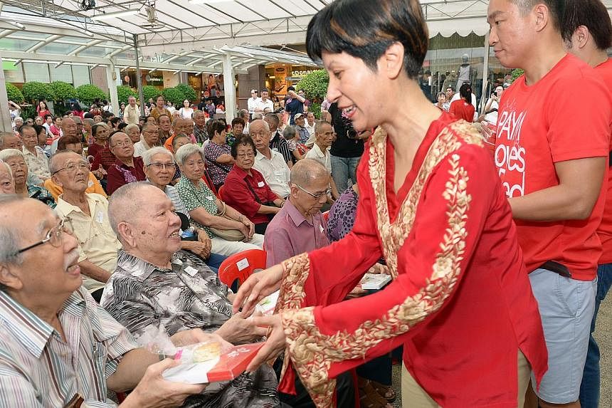 MP for Tanjong Pagar GRC Indranee Rajah hands a pioneer package to Mr Dominic Png, 76, at Tiong Bahru Plaza during a community event organized to pay tribute to Singapore's pioneer generation on Sunday, Aug 24 2014. -- ST PHOTO: DESMOND WEE