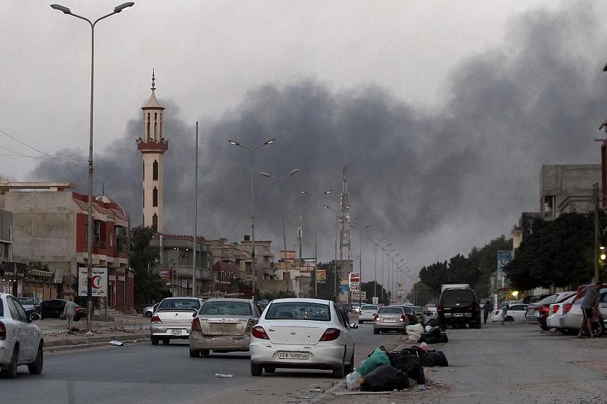 Smoke billows from buildings during clashes between Libyan security forces and armed Islamist groups in the eastern coastal city of Benghazi on Aug 23, 2014. -- PHOTO: AFP