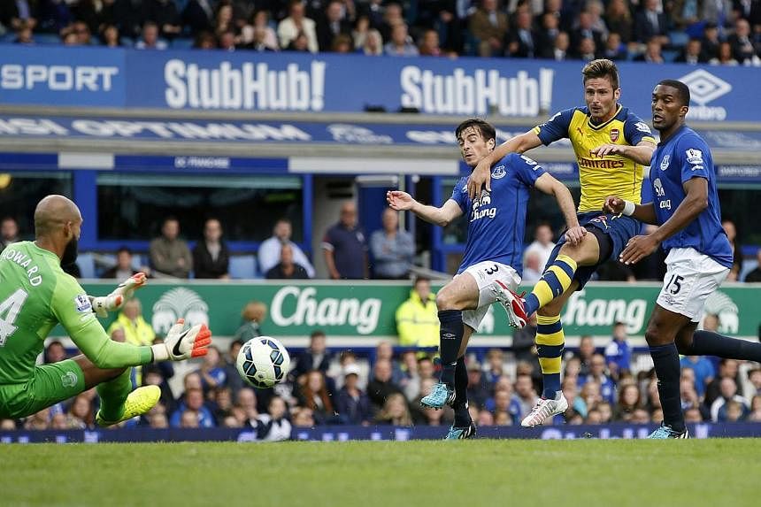 Arsenal's Olivier Giroud (second,right) is challenged by Everton's Sylvain Distin (right) and Leighton Baines (third,right) as Tim Howard (left) saves his shot during their English Premier League soccer match at Goodison Park in Liverpool, northern E