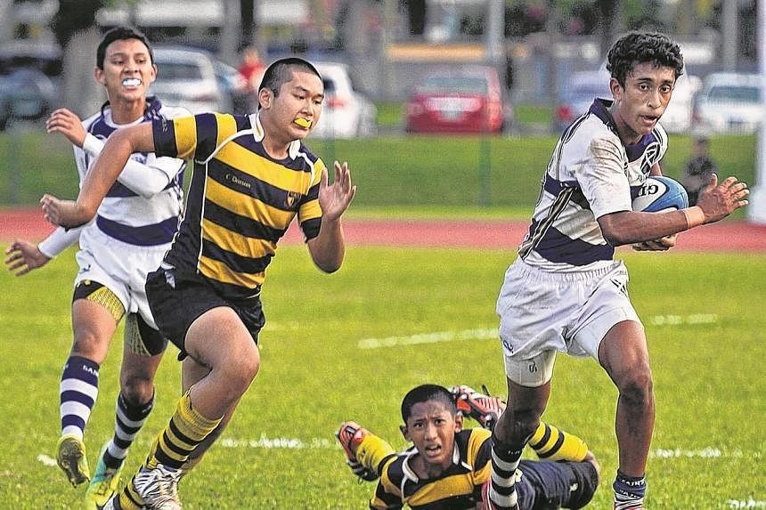 Tantham Kitiarsa (yellow and blue stripes), from Anglo-Chinese School (Independent) (ACS(I)), chasing down Viviyan Philip (right) from St Andrew’s Secondary School (SAS), during the Schools National C Division rugby championship on Aug 22, 2013. St
