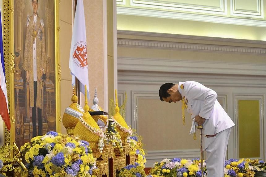 Thailand's newly appointed Prime Minister Prayuth Chan-ocha pays his respects as he receives the royal endorsement, in front of a portrait of Thai King Bhumibol Adulyadej, at the Royal Army headquarters in Bangkok in this Aug 25, 2014 handout photo p