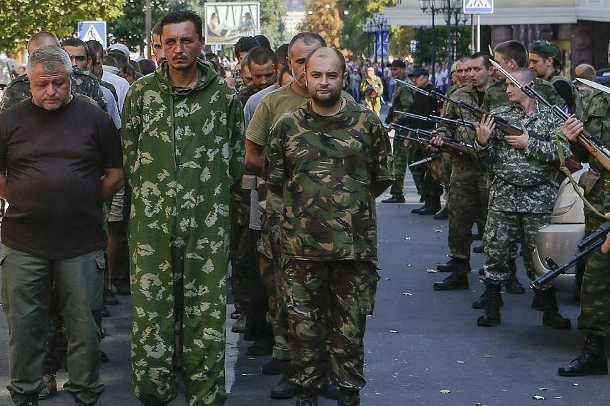 Armed pro-Russian separatists (right) escort a column of Ukrainian prisoners of war as they walk across central Donetsk on Aug 24, 2014.&nbsp;Parading Ukrainian prisoners of war through a baying crowd in a rebel-held city was not demeaning, said Russ