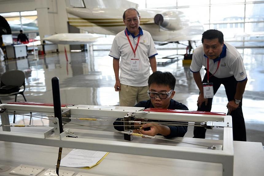 A student taking Aerospace Avionics at the Institute of Technical Education (ITE), rigs a flight control during a segment of aircraft maintainence as judges observe him at the Worldskills Singapore competition held on July 10, 2014. -- ST PHOTO: MARK