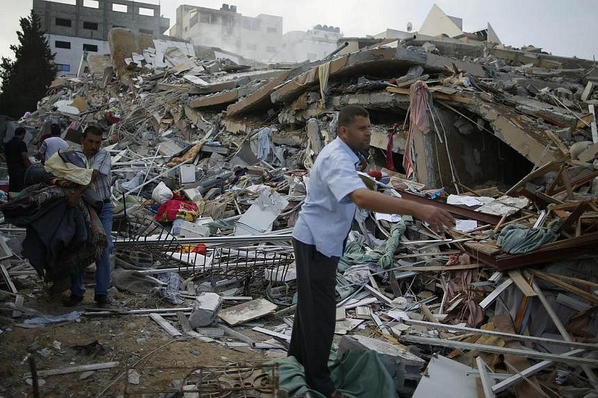 A Palestinian man looks for his belongings from under the rubble of a residential tower, which witnesses said was destroyed in an Israeli air strike in Gaza City August 24, 2014. Israel said Sunday it had killed a top Hamas financial official in an a
