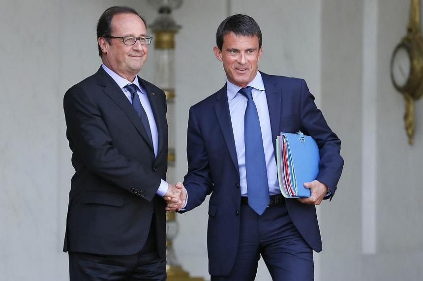 A file picture taken on Aug 20, 2014, shows French President Francois Hollande (left) and French Prime Minister Manuel Valls shaking hands at the Elysee presidential palace in Paris after a weekly cabinet meeting.&nbsp;-- PHOTO: AFP