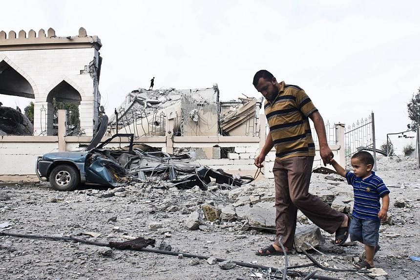 A Palestinian man walks with a child past the rubble of a mosque that was partially damaged by an Israeli airstrike on Aug 25, 2014, in Beit Lahia in the northern Gaza Strip.&nbsp;A month-long fund-raising drive by the Muslim community in Singapore h