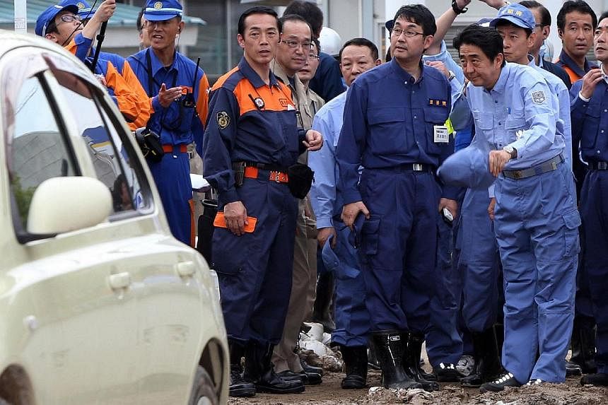 Japanese Prime Minister Shinzo Abe (right) inspects a landslide site which killed 52 people and 28 others are missing in Hiroshima, western Japan on Aug 25, 2014. -- PHOTO: AFP