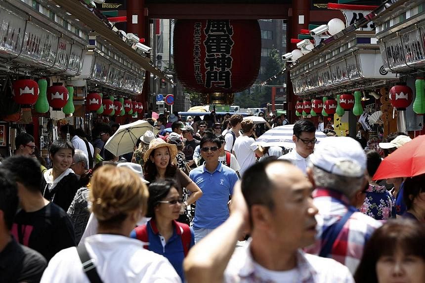 Visitors and tourists walk on a shopping street in Asakusa district in Tokyo on July 17, 2014. -- PHOTO: REUTERS