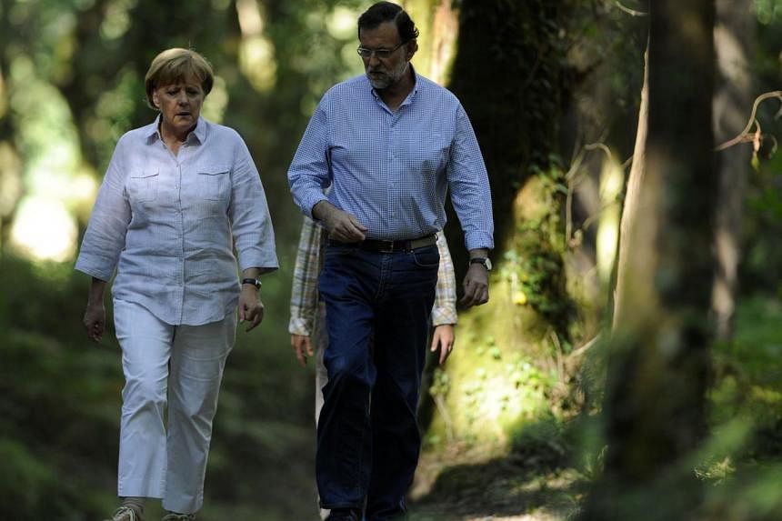 German Chancellor Angela Merkel (left) and Spanish Prime Minister Mariano Rajoy walking on the Saint James Way, near the village of Pedrouzo, some 10km from Santiago de Compostela, on August 24, 2014. -- PHOTO: AFP&nbsp;