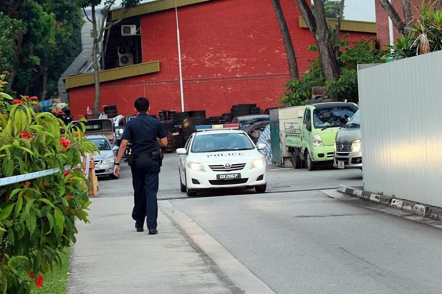 A policeman and a police car are seen near where the body of Indian national Suresh Kumar was found, at Pandan Loop, on Aug 23, 2014. A 26-year-old man was arrested on Tuesday, Aug 26, in connection with the death. -- PHOTO: SHIN MIN