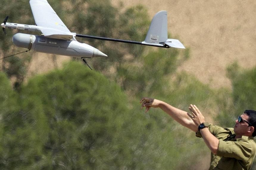 An Israel soldier launches an Israeli army's Skylark I unmanned drone aircraft, which is used for monitoring purposes, at an army deployment area near Israel's border with the besieged Palestinian territory, on Aug 4, 2014. -- PHOTO: AFP