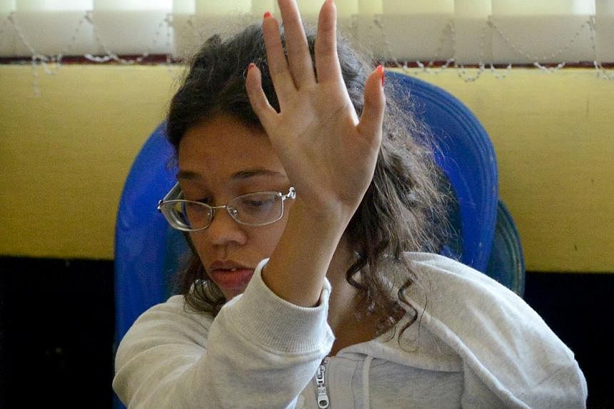 US teen Heather Mack, suspected in the murder of her mother Sheila von Wiese Mack, gestures while in custody at a police station in Denpasar on the Indonesian resort island of Bali on August 14, 2014. On Monday, Mack's US-based lawyer claimed that th