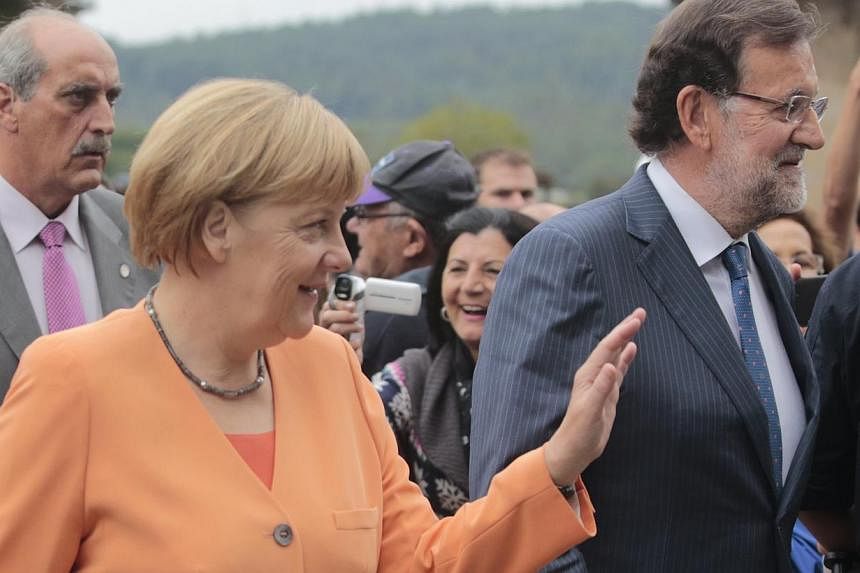 German Chancellor Angela Merkel waves next to Spanish Prime Minister Mariano Rajoy before a news conference in Santiago de Compostela, northwestern Spain, August 25, 2014. Both Merkel and Rajoy, who have been allies in stabilising the finances of hea
