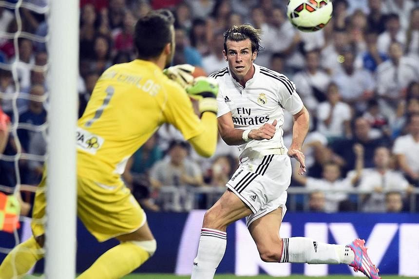 Real Madrid's Welsh forward Gareth Bale (right) shoots the ball past Cordoba's goalkeeper Juan Carlos Martin (left) during the Spanish league football match Real Madrid CF vs Cordoba CF at the Santiago Bernabeu stadium in Madrid on Aug 25, 2014. -- P