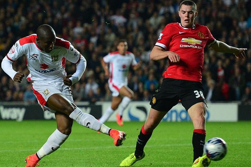 MK Dons English striker Benik Afobe (left) scores their third goal during the English League Cup second round football match between Milton Keynes Dons and Manchester United at Stadium MK in Milton Keynes, north of London, on Aug 26, 2014. -- PHOTO: 