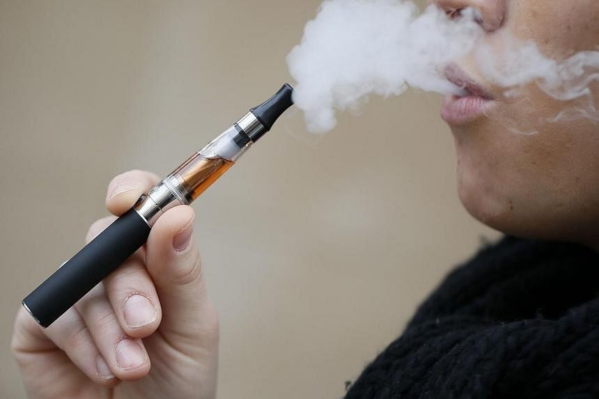 A person smokes an electronic cigarette on March 5, 2013, in Paris.&nbsp;The World Health Organisation (WHO) called for stiff regulation of electronic cigarettes as well as bans on indoor use, advertising and sales to minors, in the latest bid to con