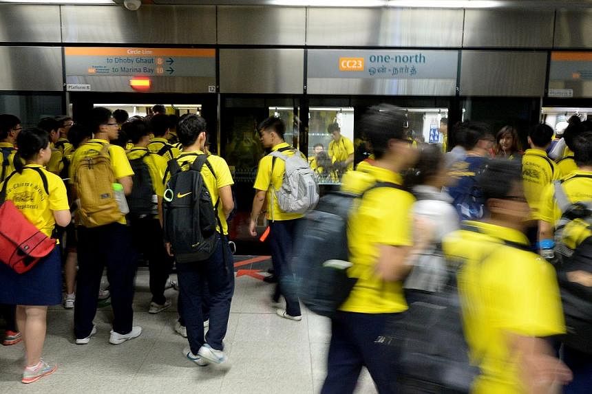 ACS (I) students boarding one of the five trains that the school had chartered to ferry them from One North station to the new National Stadium to catch their National C Division rugby match against St Andrew's Secondary on Aug 26, 2014. -- ST PHOTO: