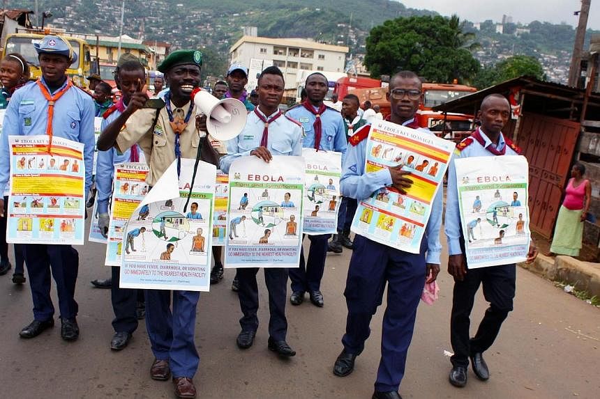Members of a UNICEF-supported social mobilisation team walk on a street, carrying posters with information on the symptoms of Ebola and best practices to help prevent its spread, in Freetown, Sierra Leone, in this handout photo courtesy of UNICEF tak